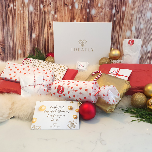 Gift box and 12 vegan xmas gifts wrapped in Christmas themed tissue