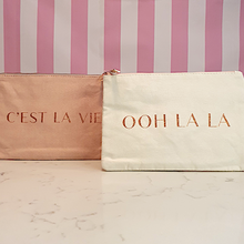 Load image into Gallery viewer, A pink makeup bag with "C'est la vie" slogan and a cream coloured makeup bag with an "ooh la la" slogan